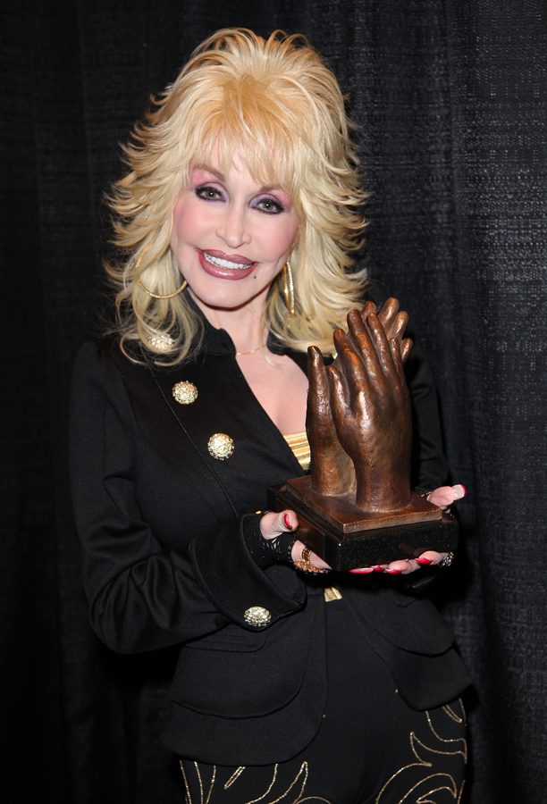 Dolly Parton segurando um troféu em formato de mão, em 2010.